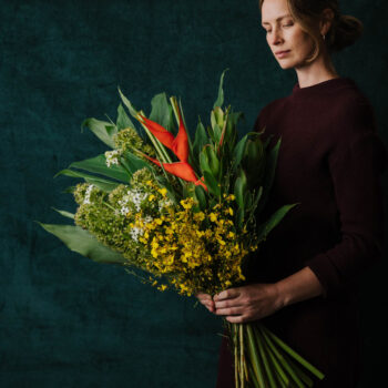 large forward facing bouquet made with bright yellow red and white seasonal flowers and backing foliage to frame the bouquet