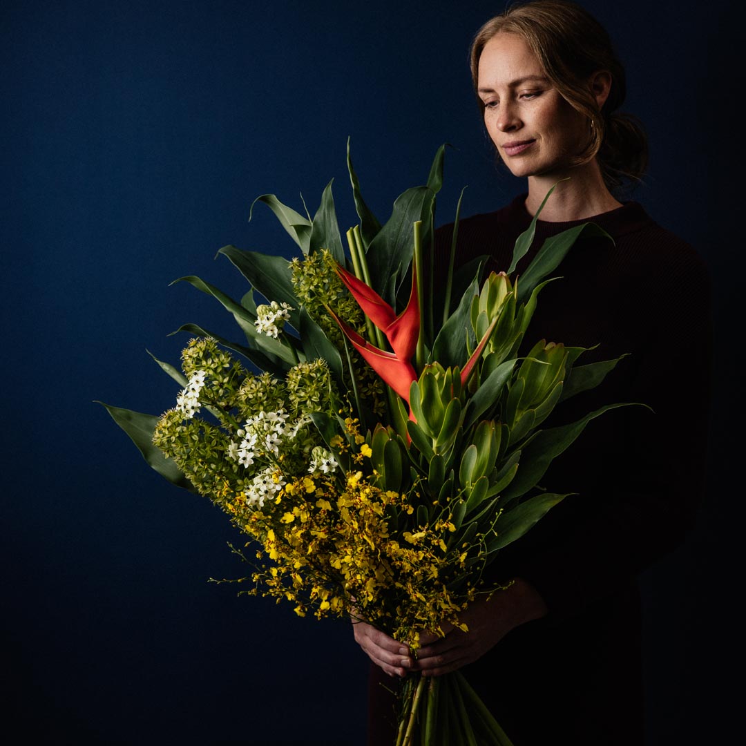 large forward facing bouquet made with bright yellow red and white seasonal flowers and backing foliage to frame the bouquet